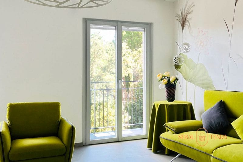 Un soggiorno con arredi verdi e Serramenti in alluminio Lodi.
