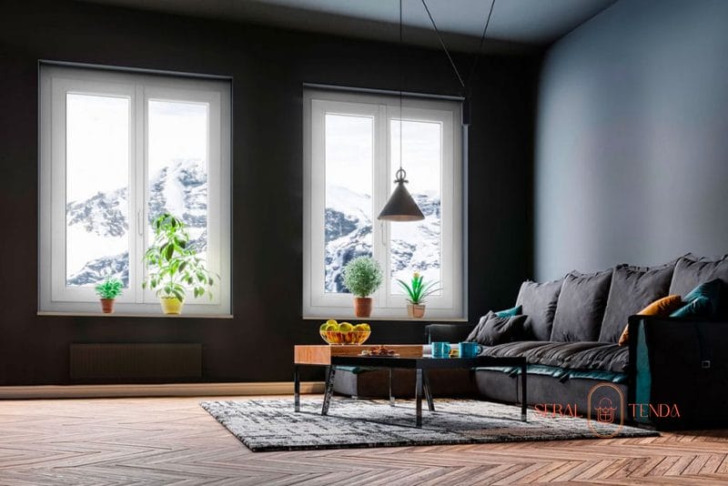 Un soggiorno con un divano nero e vista sulle montagne. La camera dispone di eleganti finestre Serramenti in alluminio Lodi, che offrono viste mozzafiato sulle maestose montagne esterne.