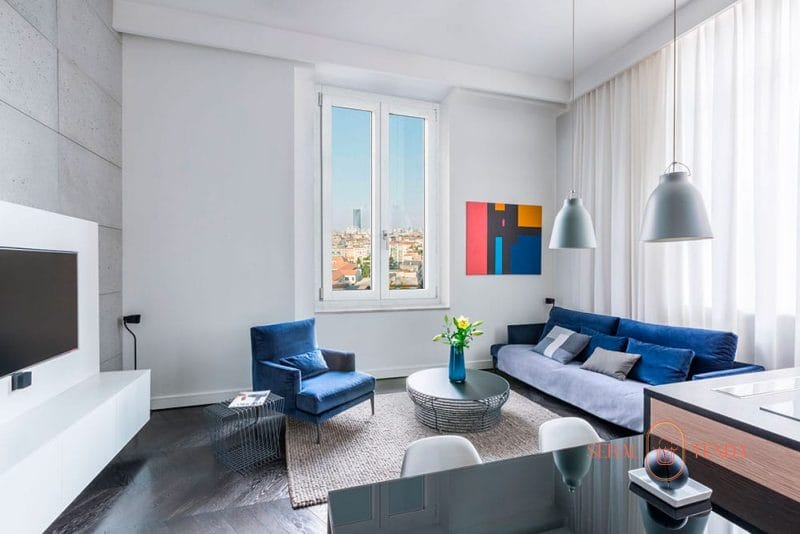 Un soggiorno con divano blu e TV, caratterizzato da eleganti infissi in alluminio Lodi.