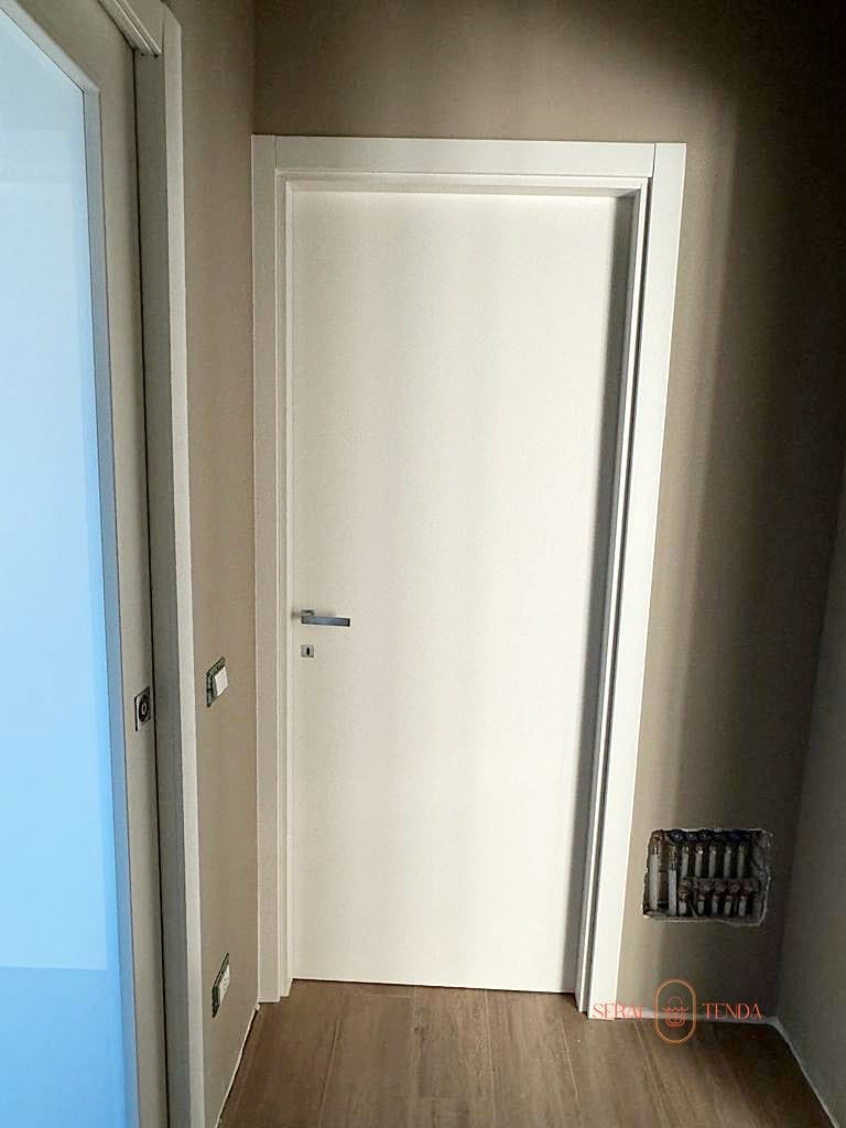 Una porta bianca in una stanza con pavimenti in legno. (Door 2000)
