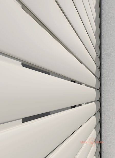 Vista ravvicinata di listelli bianchi orizzontali con fessure, che ricordano le eleganti tapparelle, posizionati ad angolo contro una parete.