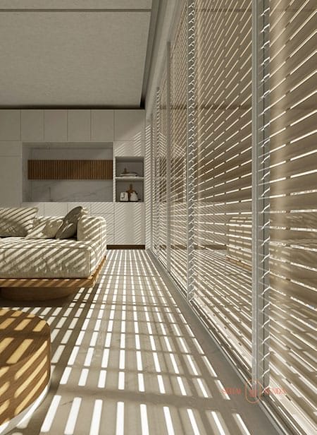 La luce del sole filtra attraverso le tapparelle, proiettando ombre a strisce su un soggiorno moderno con un divano beige e mobili bianchi.